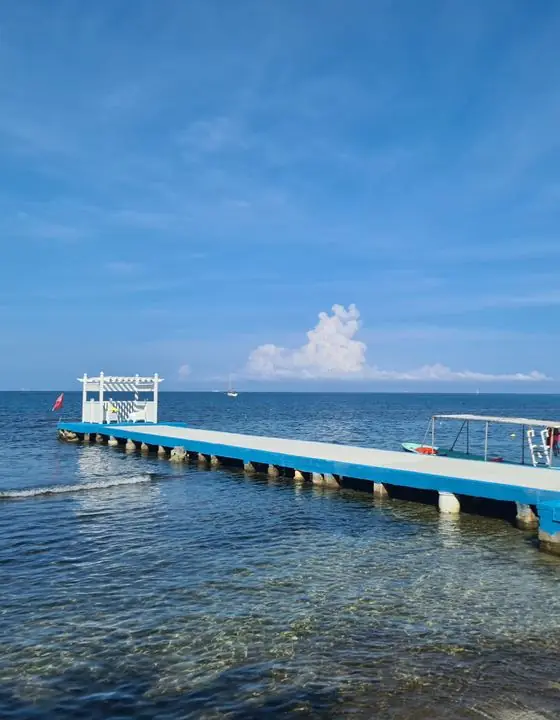 Muelle azul sobre el mar Caribe con un islote al fondo