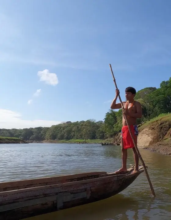 Joven emberá navegando en piragua por el río