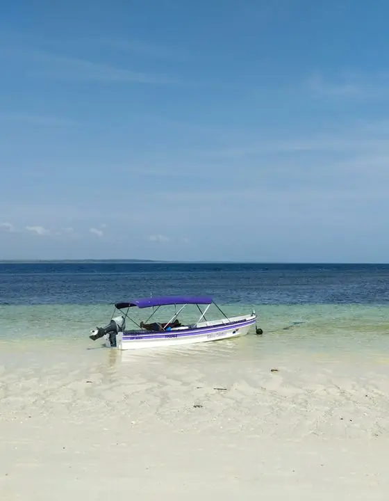 Lancha sobre una playa de arena blanca y aguas transparentes