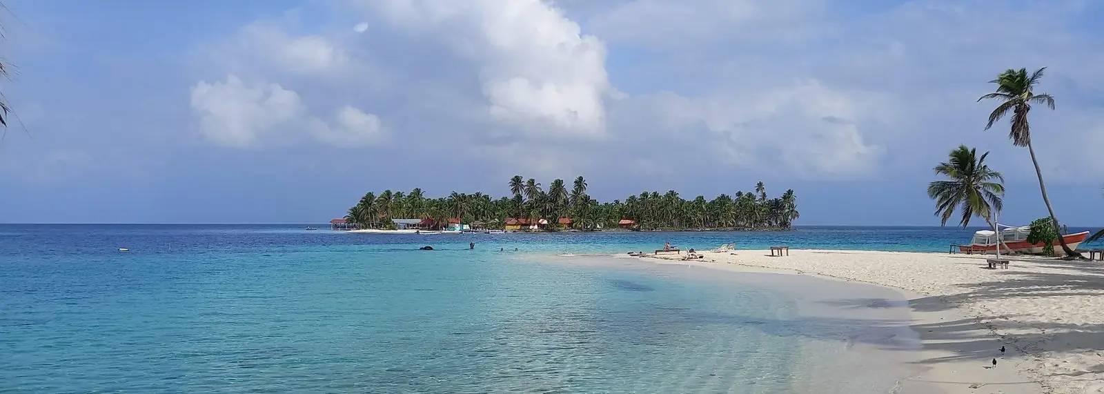 Playa de arena blanca y aguas turquesa en San Blas, con una isla de palmeras al fondo