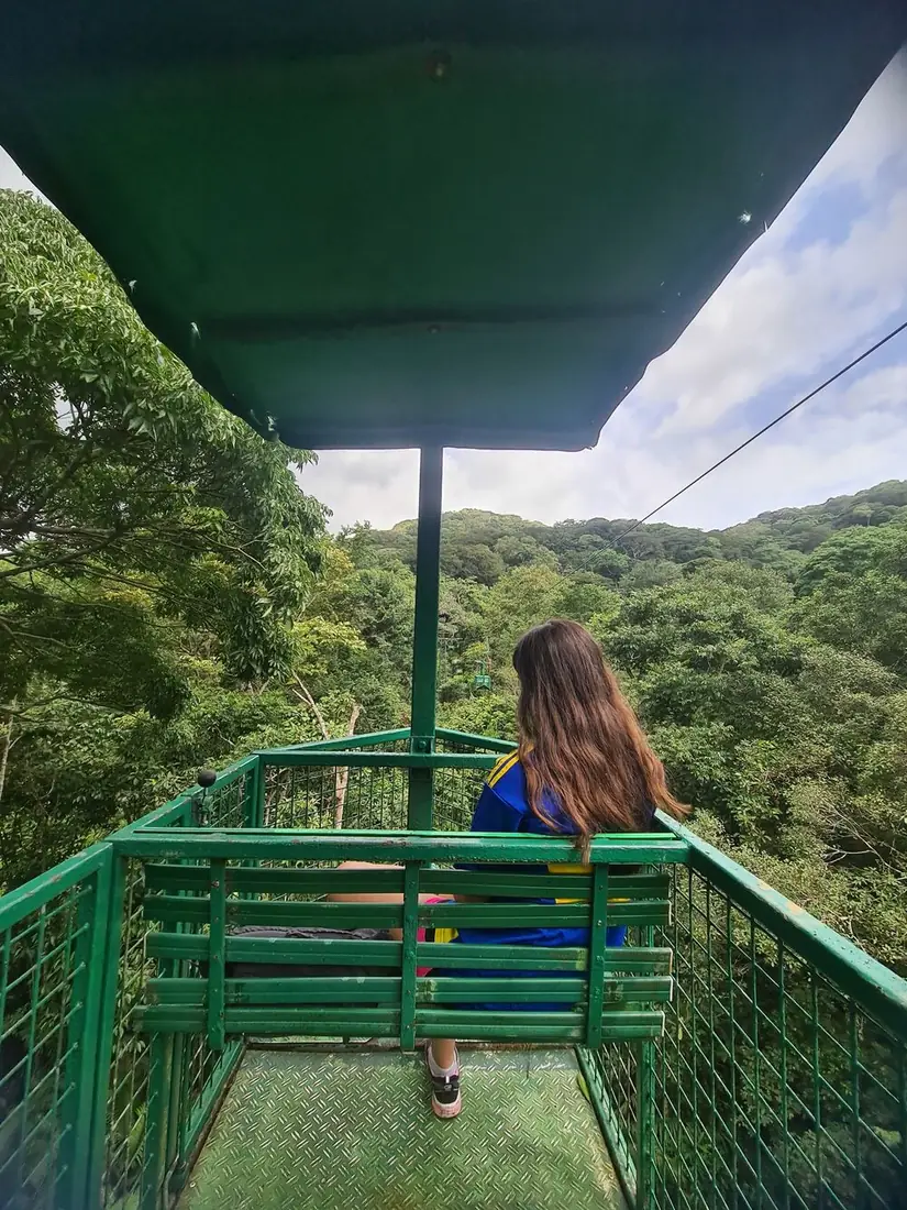 Viajera de espaldas en el teleférico sobre el bosque tropical