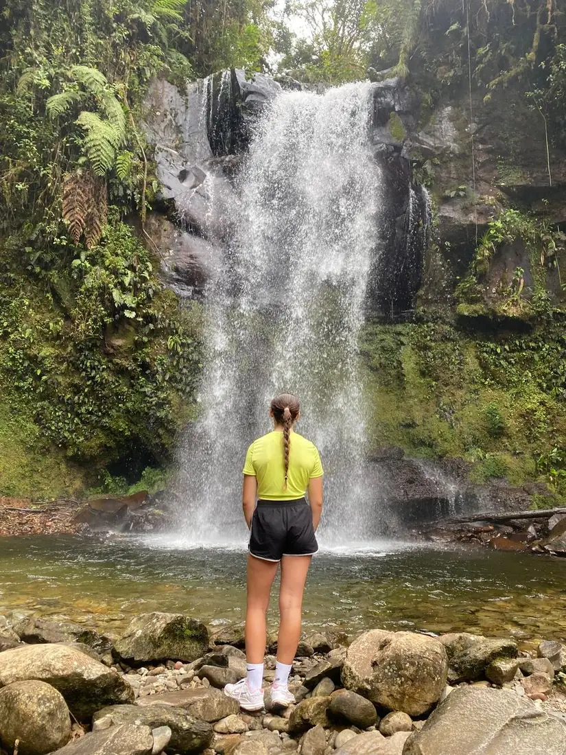 Viajera de espaldas frente a una cascada en la selva
