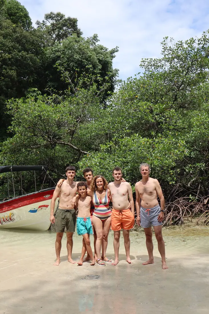 Familia de seis en bañador junto a los manglares, con una lancha al lado
